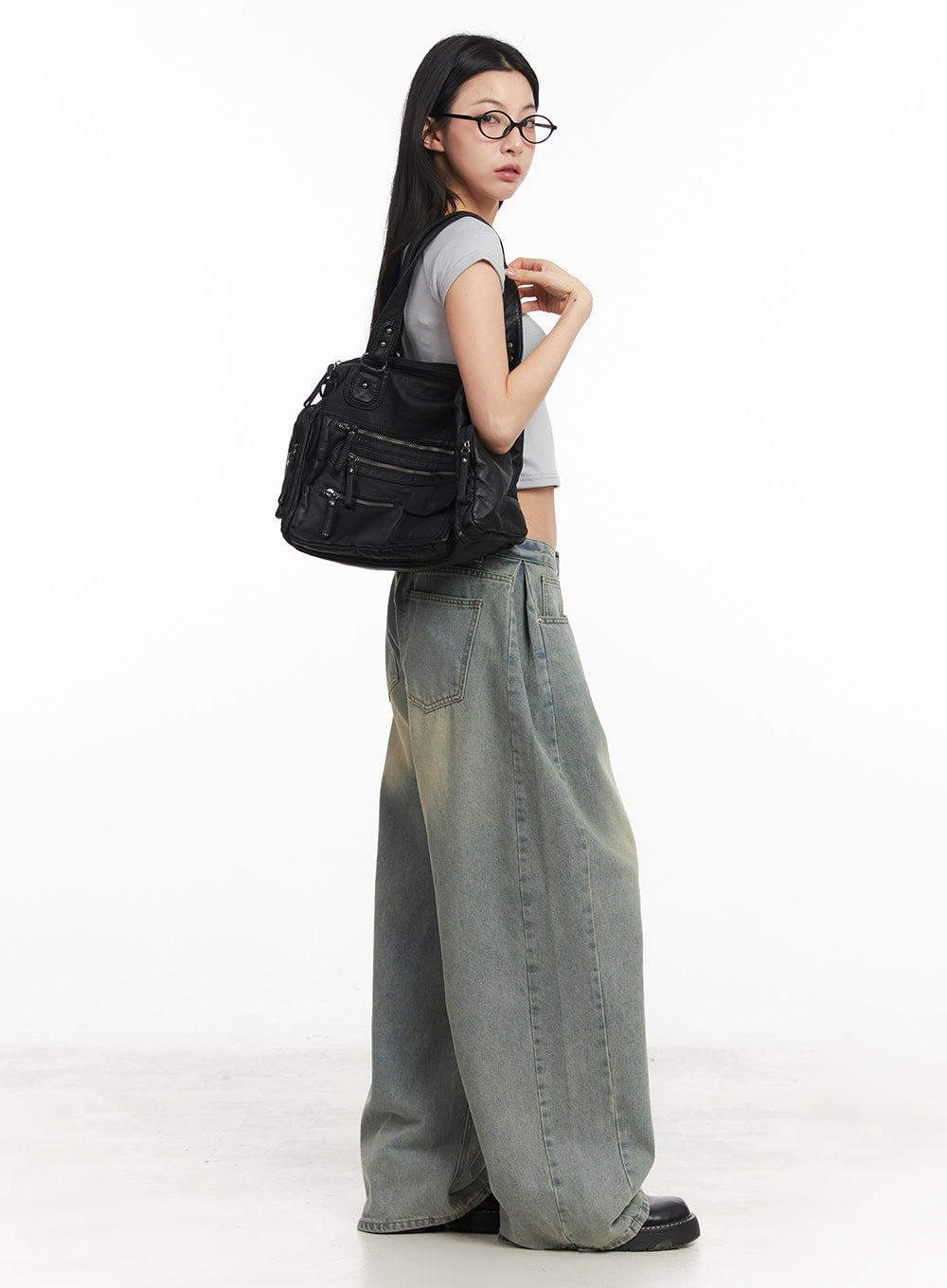 Hillary Washed Wide-Leg Jeans CM504 in light blue, side-angle full-body shot on model looking back, washed baggy denim paired with grey crop tee and black multi-pocket bag.