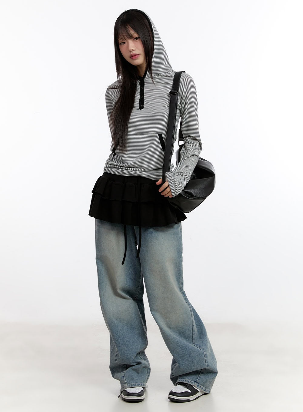 Jillie Washed Baggy Jeans CA508 in blue, full-body front shot on model, wide-fit washed denim pooling at hem, styled with striped hoodie, ruffle skirt overlay, and black shoulder bag.