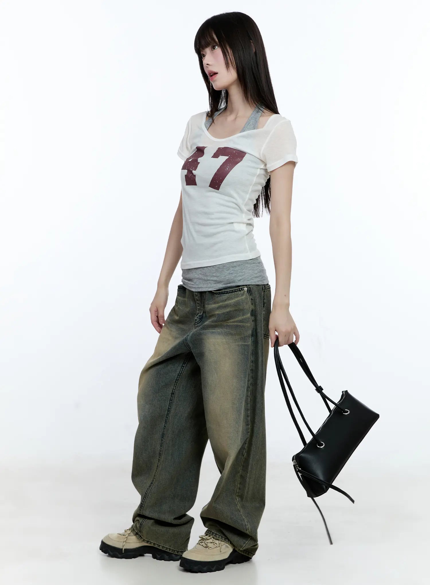Yeonsoo Vintage-Wash Wide-Leg Jeans CG507 in vintage blue, three-quarter side view on model holding black bag, styled with a white graphic tee layered over grey halter top.