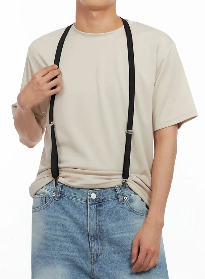 Men's Classic Black Suspenders IL516 in black, front close-up on model gripping strap, silver adjuster hardware visible, styled over beige tee with blue jeans.