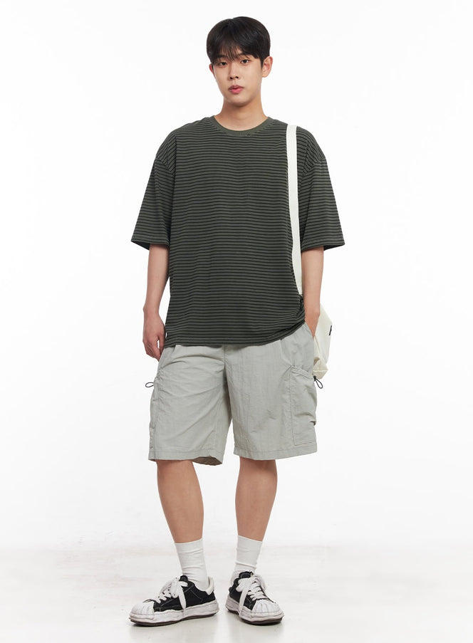 Men's Cotton Striped Round-Neck T-Shirt IY522 in dark green, full-body front on model, drop-shoulder cotton tee, styled with cargo shorts, white sneakers, and a white crossbody bag.