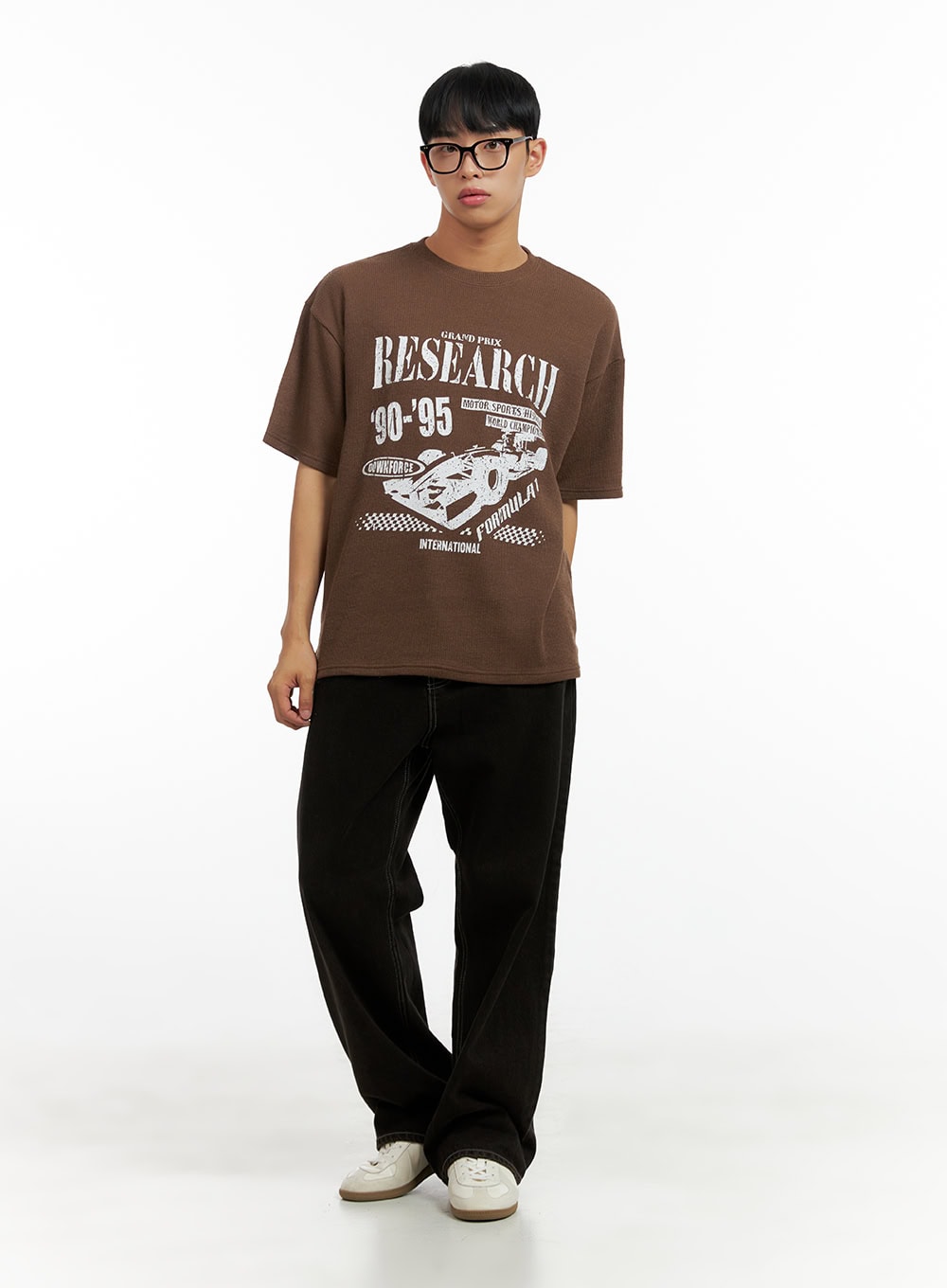 Men's Wide Fit Washed Baggy Jeans CL429 in Black, full-body front view on male model, relaxed baggy silhouette, styled with brown graphic tee and white sneakers.