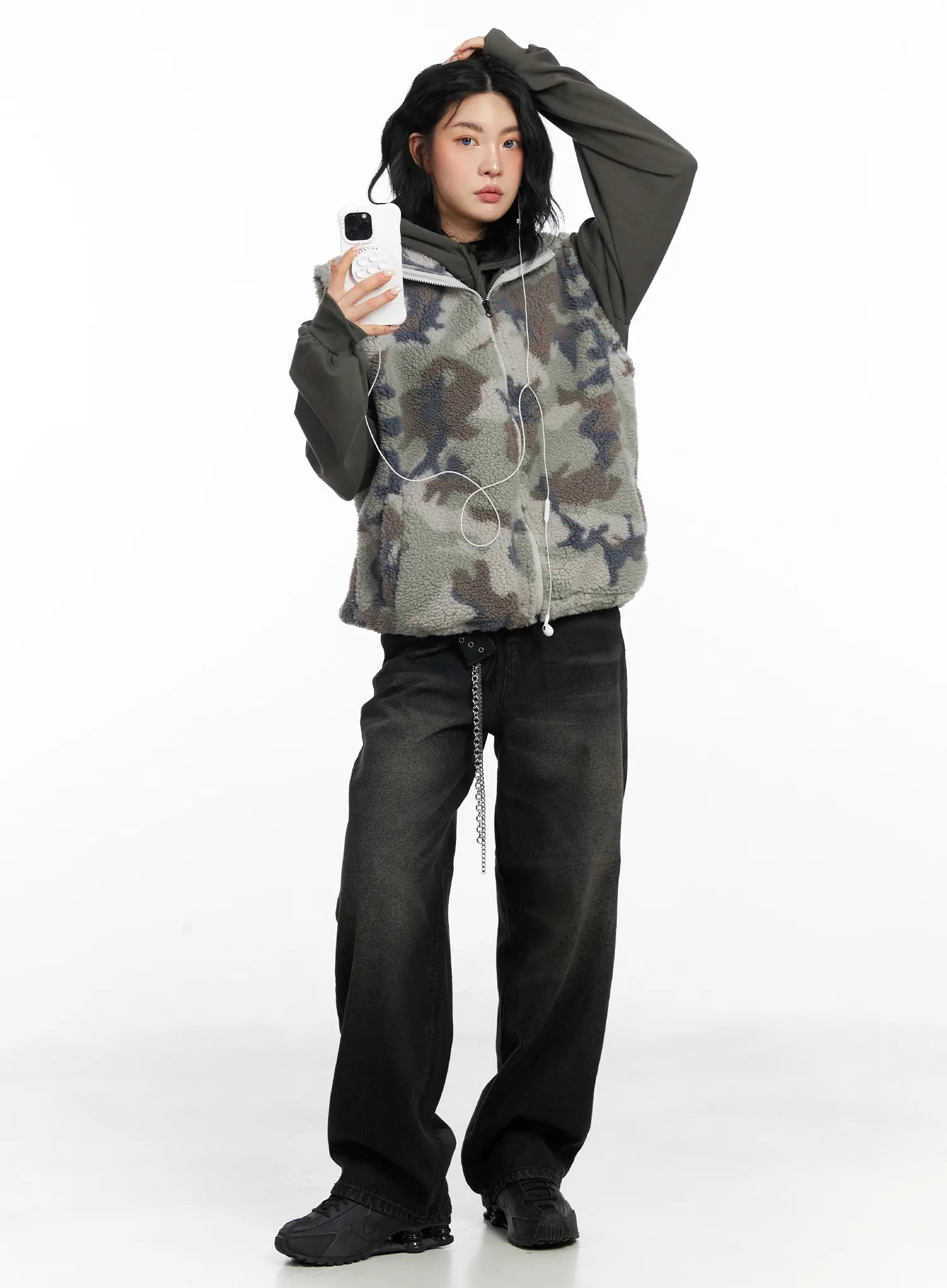 Dayana Vintage Washed Wide-Leg Jeans CJ523 in black, full-body editorial shot, model holding phone, styled with camo sherpa vest and dark hoodie, relaxed wide-leg silhouette.