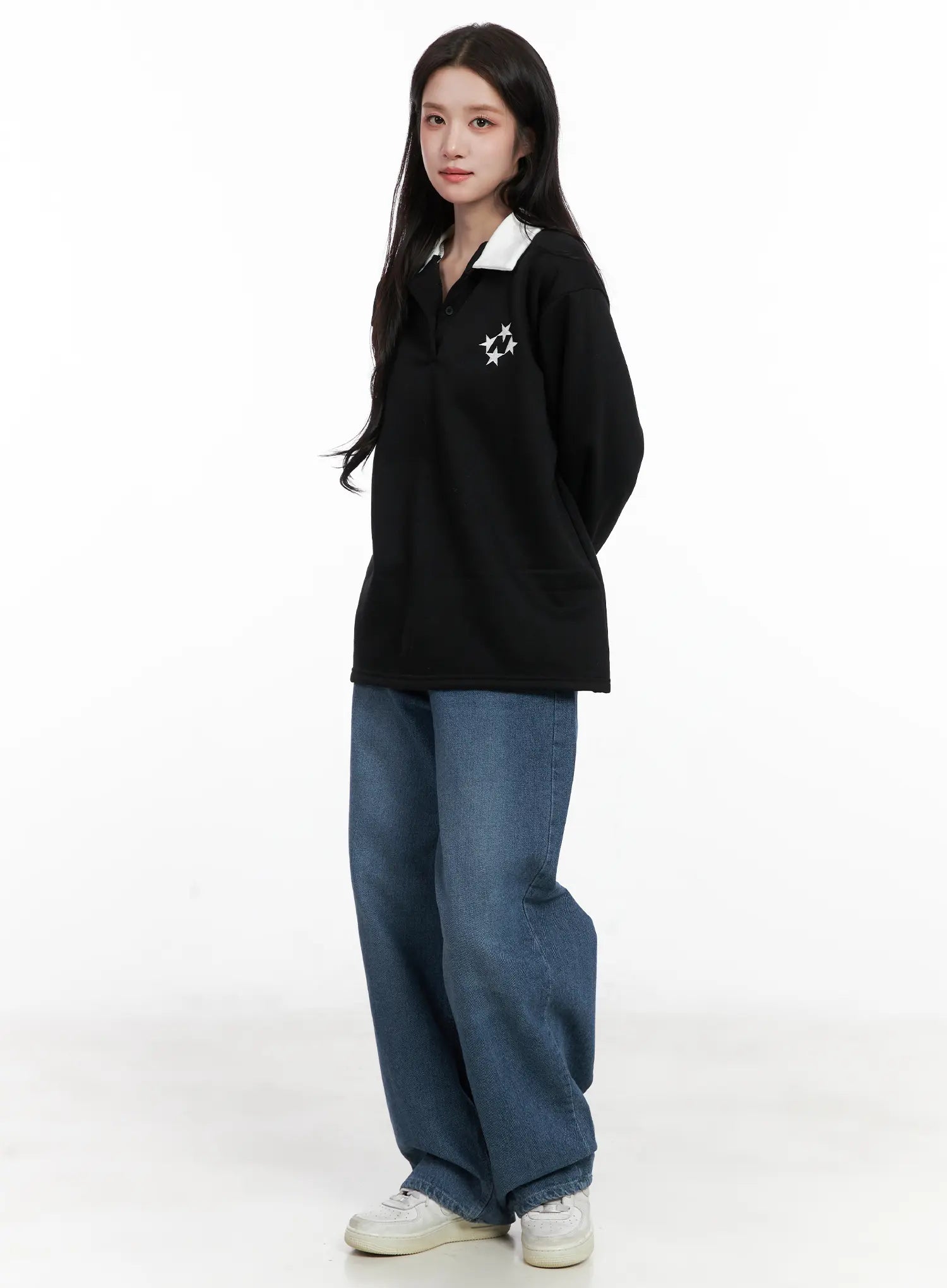 Mariam Baggy Jeans CN526 in blue, 3/4 front view on model, loose wide-leg washed denim pooling at hem, styled with black polo sweatshirt and white sneakers.