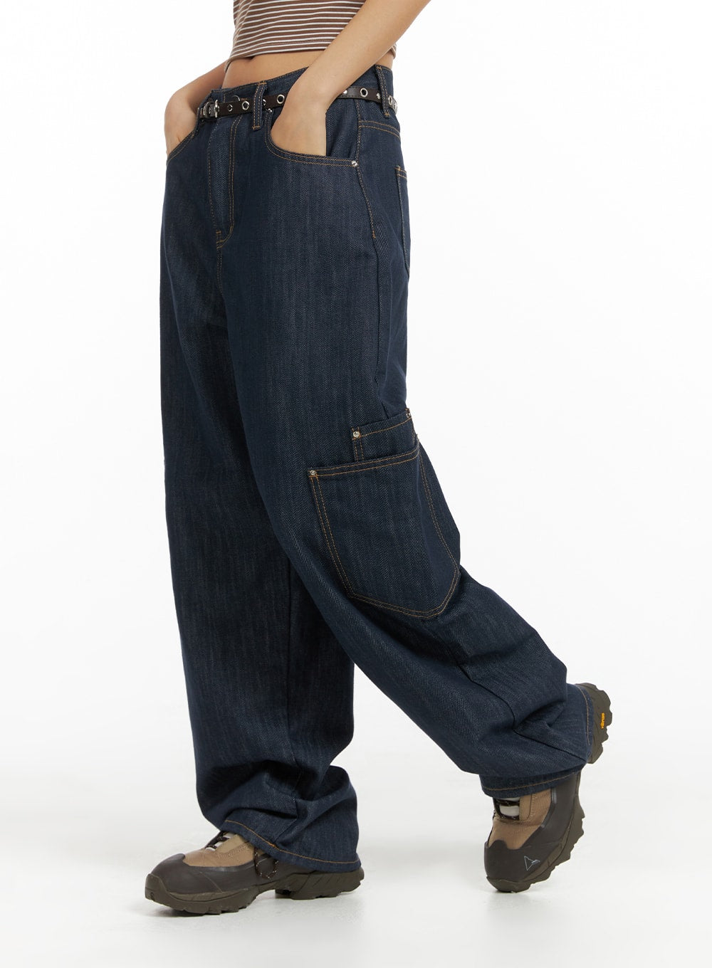 Pocketed Denim Wide Leg Jeans CF423 in dark blue, side view on model mid-stride, wide leg silhouette with side cargo pocket, contrast topstitching, eyelet belt, paired with chunky sneakers.