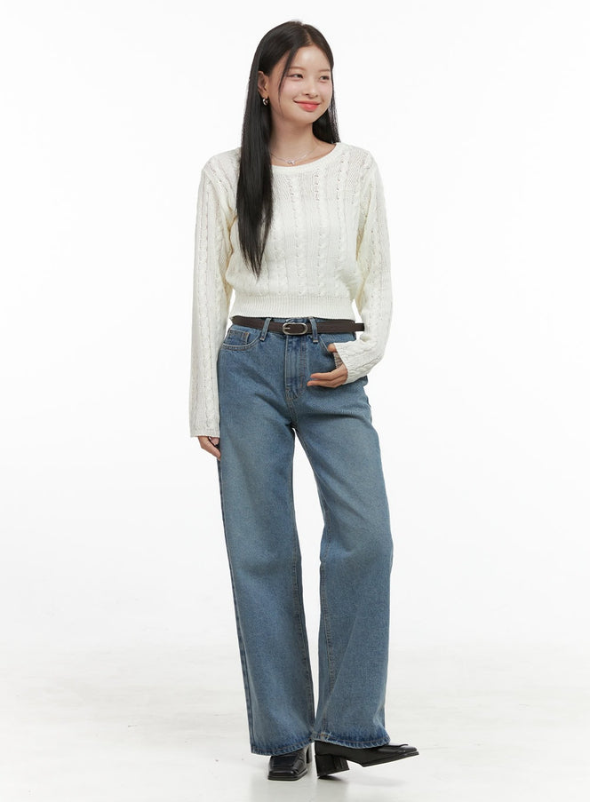 SoftTouch Wool Blend Top OS411 in light beige, full-length front shot on model smiling, cropped cable-knit top with ribbed hem, styled with wide-leg blue jeans and brown belt.
