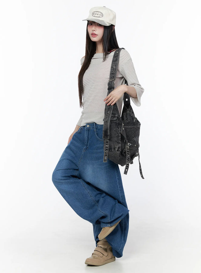Tommie Wide Leg Jeans CU519 in blue, full-body angled shot on model, oversized balloon silhouette, styled with striped tee, cap, and dark denim backpack.
