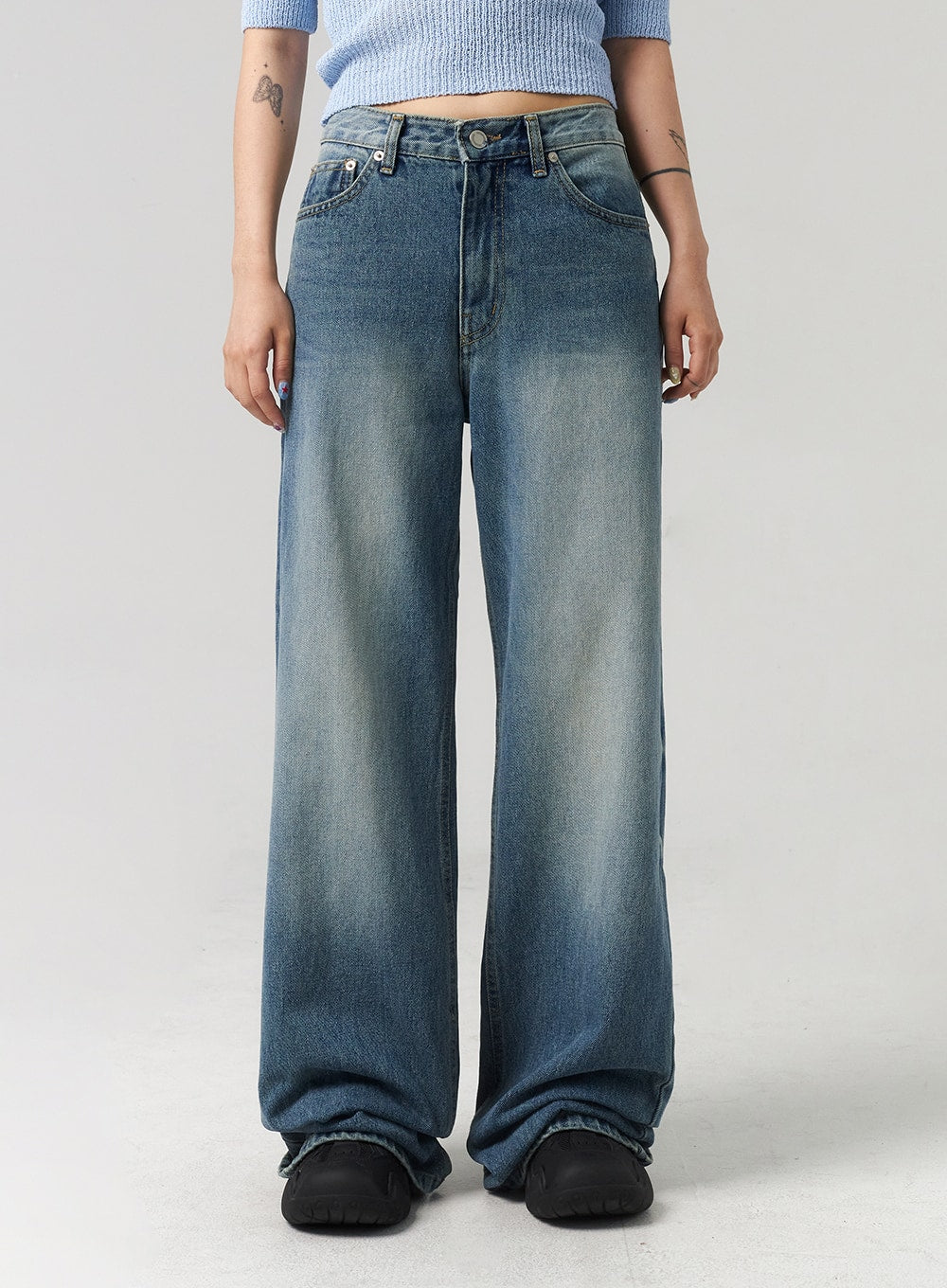 Mid-Wash Baggy Jeans CL312 in mid-wash blue, front close-up on model, low-rise waistband with button fly, wide baggy leg silhouette with subtle fading, hem pooling at floor.