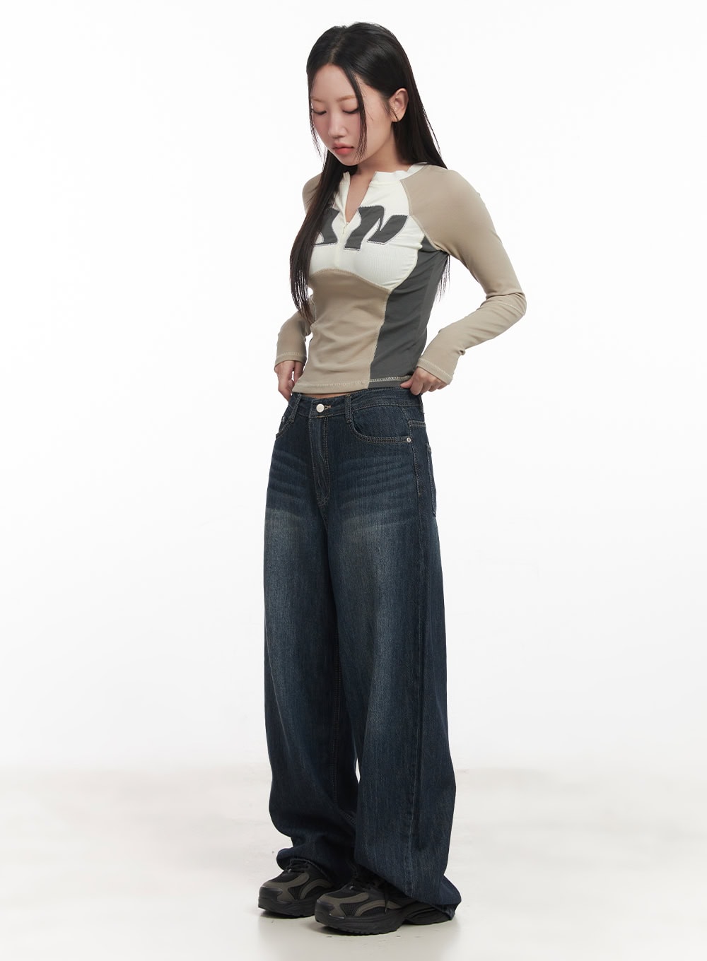 Renna Baggy Jeans CA521 in dark blue, full-length 3/4 angle on model looking down, ultra-wide washed denim silhouette styled with a graphic colorblock long-sleeve top.