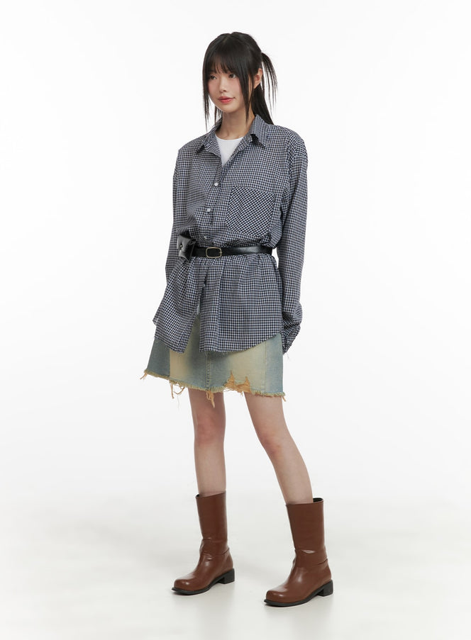Vintage Destroyed Hem Mini Skirt CA418 in light blue, full-body editorial shot on model, styled with plaid shirt and black belt, frayed destroyed hem, brown knee-high boots.