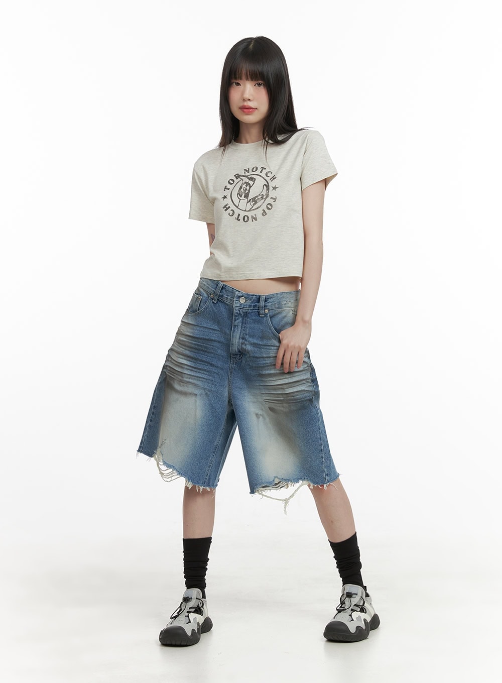 Destroyed Hem Bermuda Jorts CY414 in blue, full-body front shot on model, midi wide-fit washed denim with destroyed hem, paired with beige graphic crop tee, black socks, and chunky sneakers.