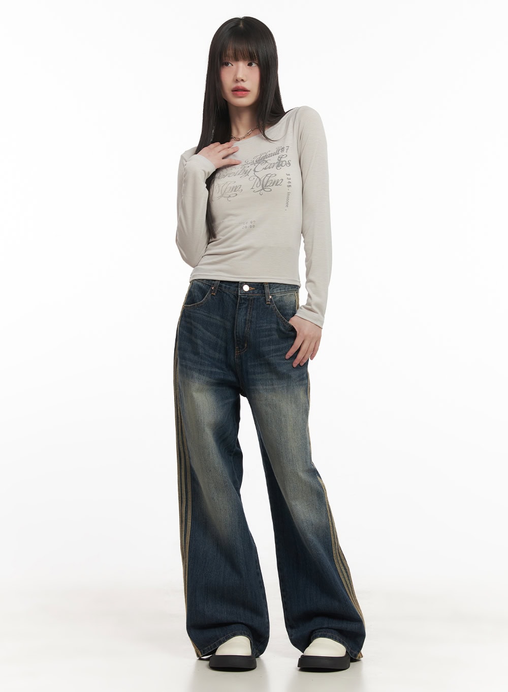 Daisee Striped Wide-Leg Jeans CF518 in dark blue, full front view on model, wide-fit washed denim with side triple stripes, styled with beige graphic long-sleeve top and white platform shoes.