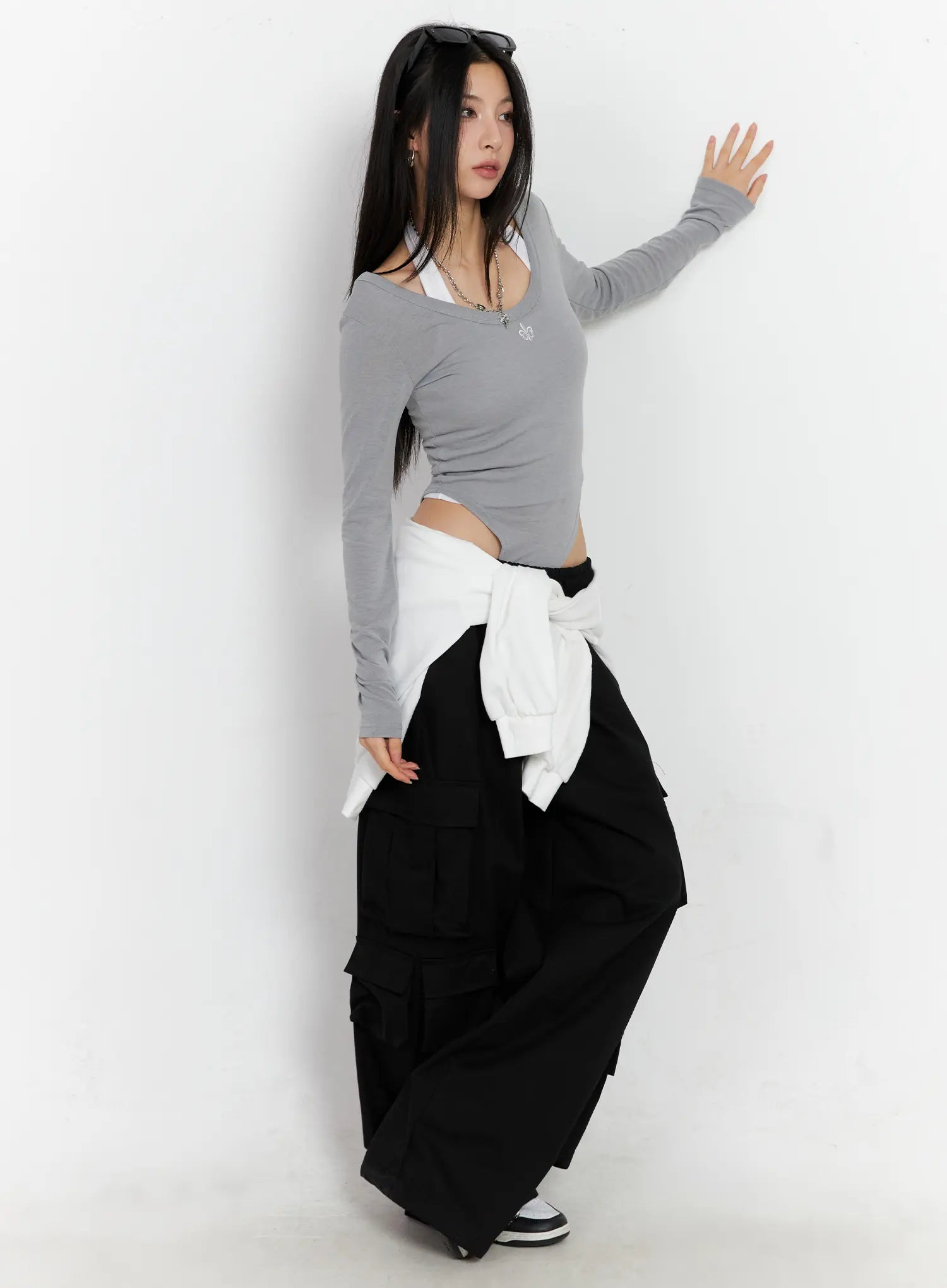 Wide Leg Cargo Pants CC1109 in black, 3/4 side editorial shot on model, styled with grey crop top and white hoodie tied at waist, oversized street silhouette.
