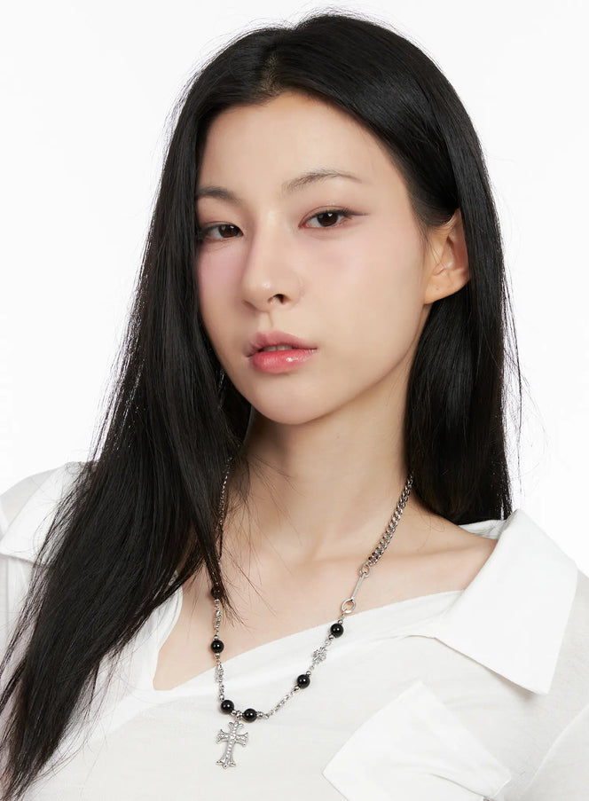 Gothic Cross Pendant Necklace CG526 in silver, front portrait on model facing camera, gothic cross pendant, black bead and flower-link chain visible, paired with white wide-collar top.
