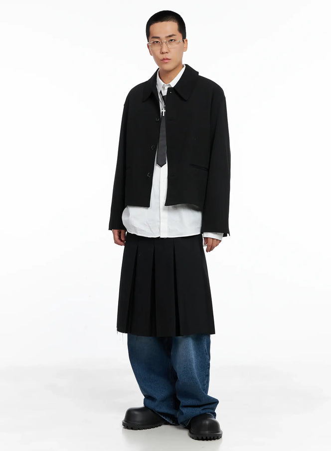 Men's Cross Pendant Necklace IS502 in Black, full-body editorial on model, silver chain visible under black jacket layered over white shirt and tie.
