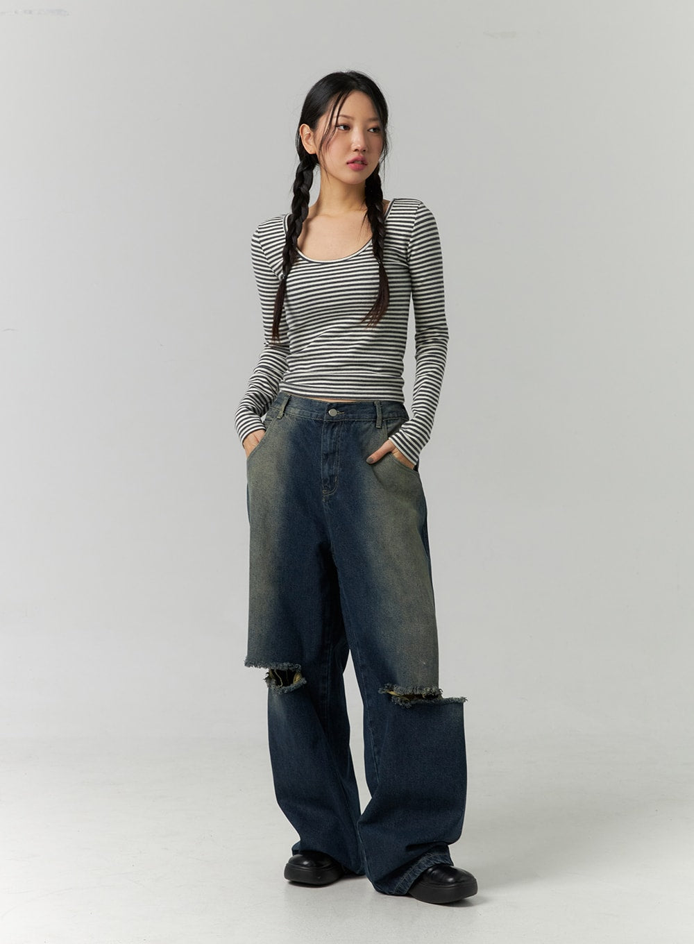 Destroyed Washed Wide Leg Jeans CN324 in dark blue, front three-quarter shot on model, hands in pockets, wide-leg silhouette with dual destroyed knee cutouts and vintage wash gradient, styled with stripe top.