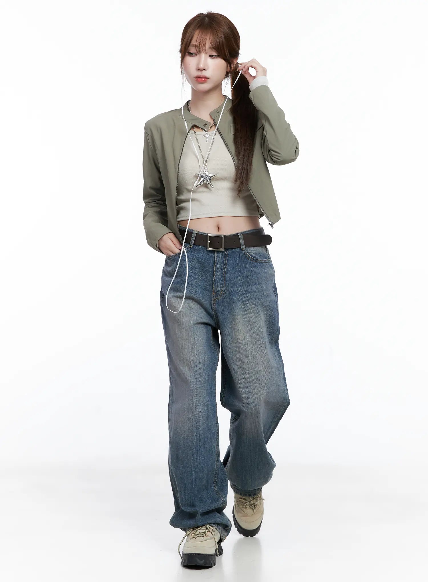 Lala Wide Leg Vintage Washed Jeans CG529 in blue, full-body editorial shot on model walking, styled with green crop jacket, beige tank, brown belt, and hiking shoes.