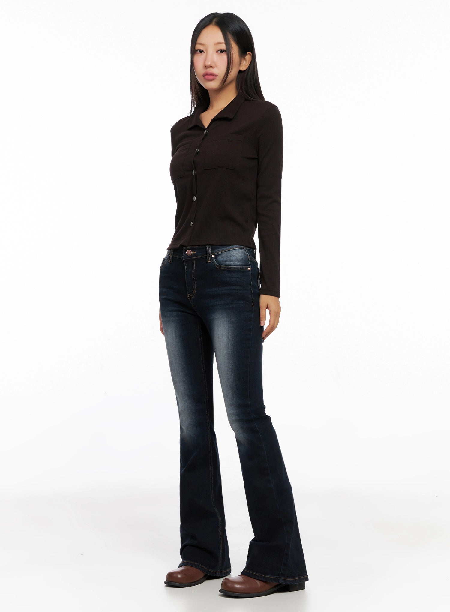 Aliyah Mid-Rise Hip Pad Flared Jeans IG528 in dark blue, 3/4 angle full-body on model, washed flared hem highlighted, styled with dark brown button-up knit top and brown boots.