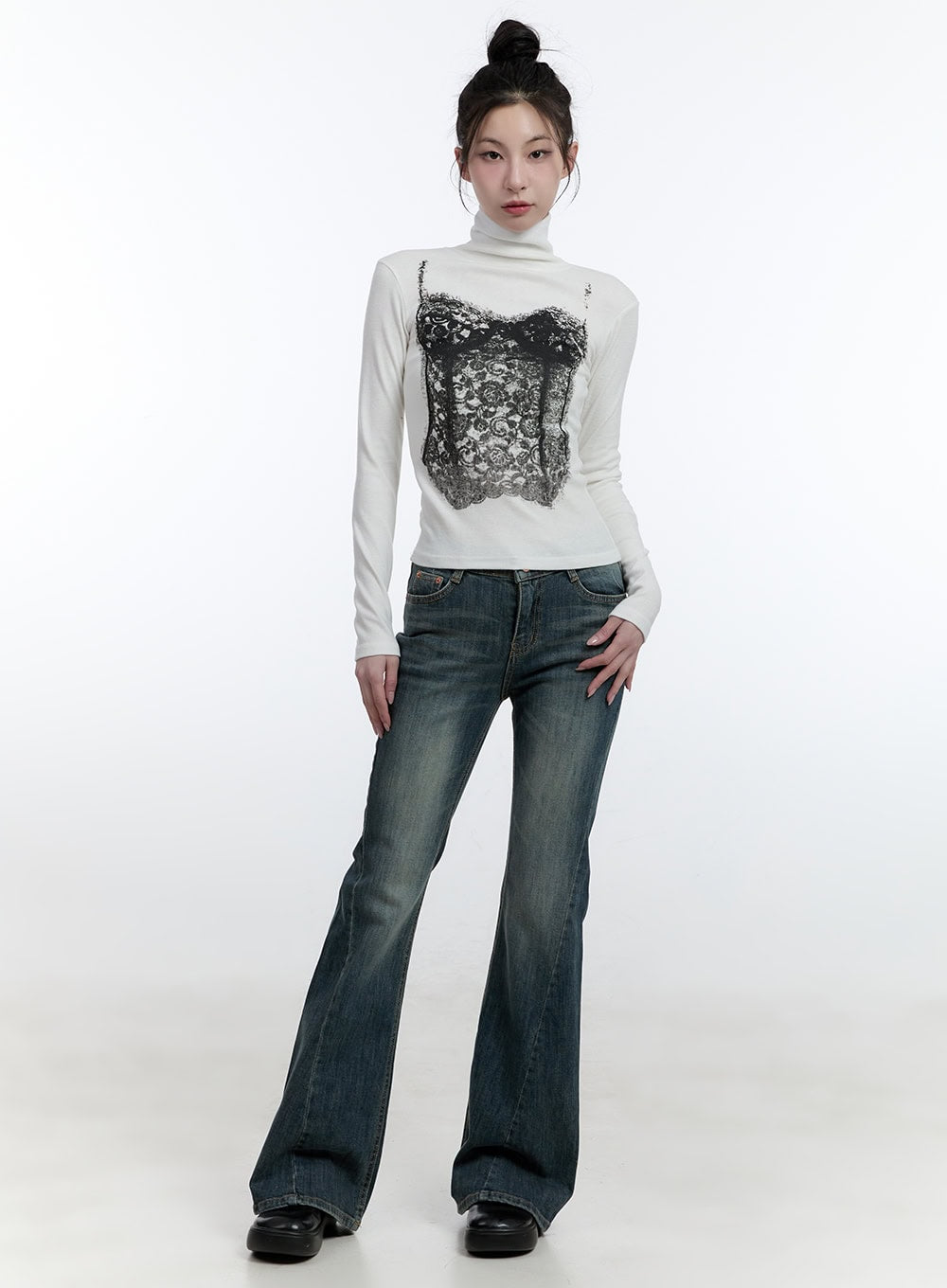 Mallory Skinny Bootcut Jeans CJ520 in blue, full-body front shot on model, low-rise washed denim with slim bootcut silhouette, styled with white graphic turtleneck and black shoes.