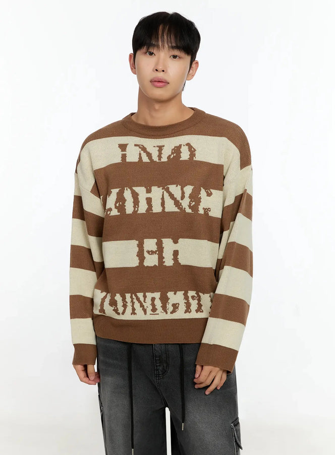 Men's Graphic Striped Sweater IN506 in brown and cream, front view on model, wide horizontal stripes with distressed letter jacquard, crewneck, paired with dark cargo jeans.