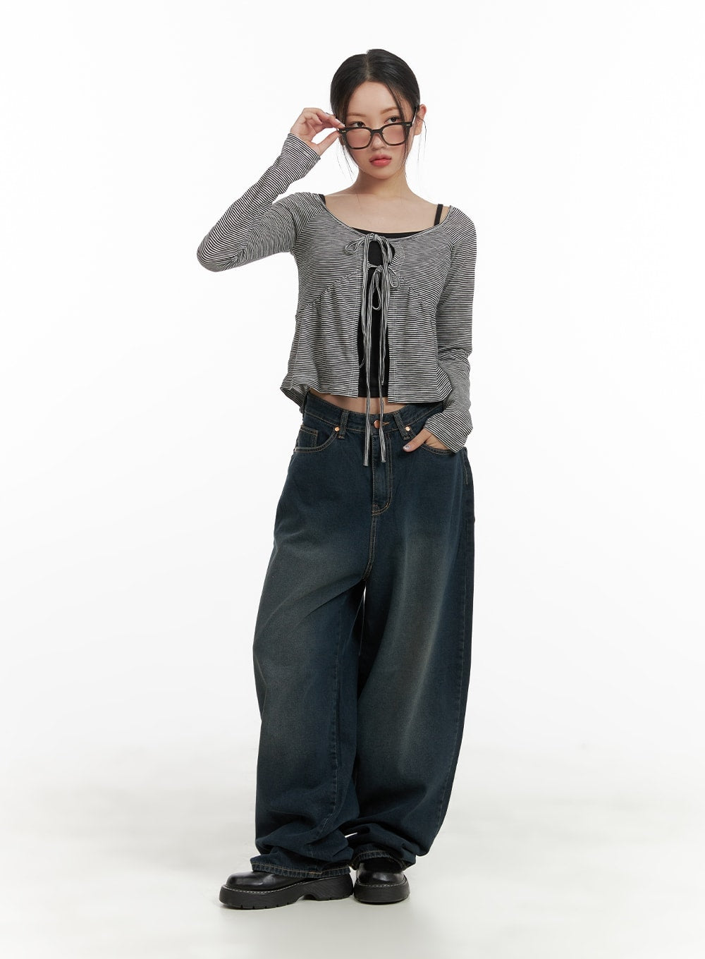 Washed Denim Baggy Jeans CA415 in blue, full-body front view on model, ultra-wide baggy silhouette with washed cotton denim, styled with striped lace-up crop top and chunky black shoes.