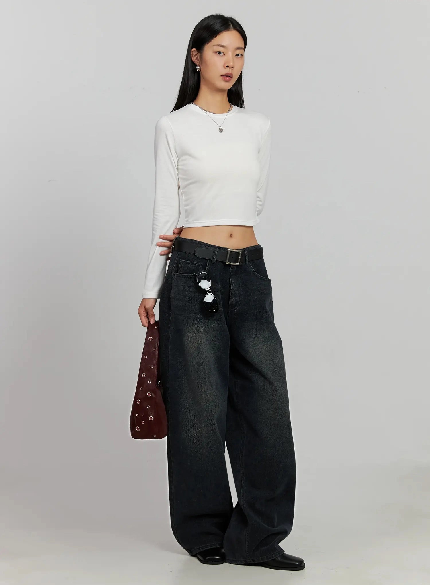 Aubree Washed Wide Jeans IJ502 in dark blue, full-body angled shot on model, styled with white crop long-sleeve top, belt, sunglasses hooked on waistband, and burgundy studded bag.