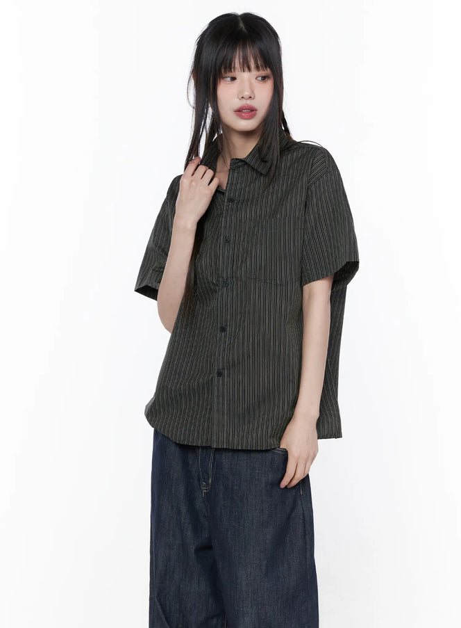 Oversized Short Sleeve Button-Up Shirt CU519 in dark charcoal, three-quarter front view on model, vertical stripe woven fabric, relaxed boxy fit, buttoned up, paired with dark wide-leg denim jeans.