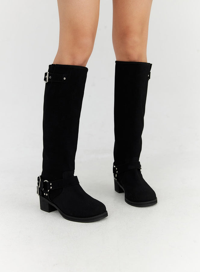 Buckle Faux Leather Boots CN315 in black, slightly angled front view on model, both boots shown, silver top buckle and studded ankle harness strap, low block heel.