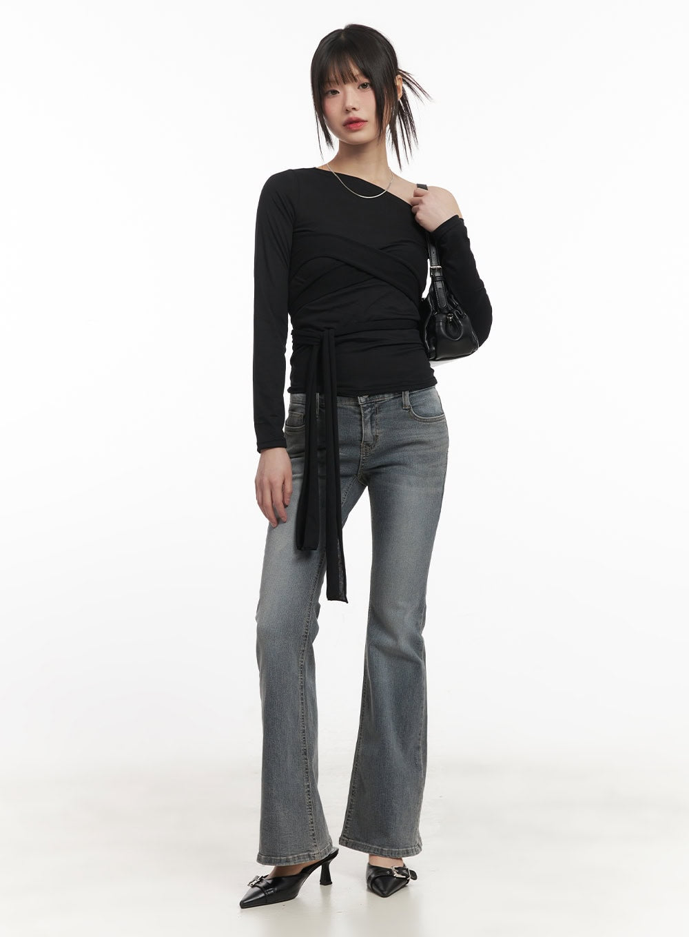 Rachel Washed Bootcut Jeans with Hip Pads CF518 in gray, full-body front shot on model, low-waist bootcut flare denim styled with black long-sleeve tie top and mini bag.