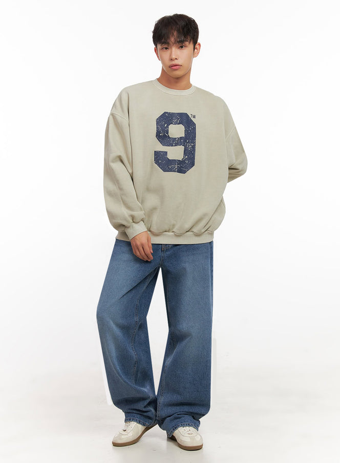 Men's Casual Long-Sleeve Oversized Tee ID427 in beige, full-body front view on model, oversized crewneck with vintage navy 9 graphic, ribbed hem, styled with wide-leg blue jeans and white sneakers.