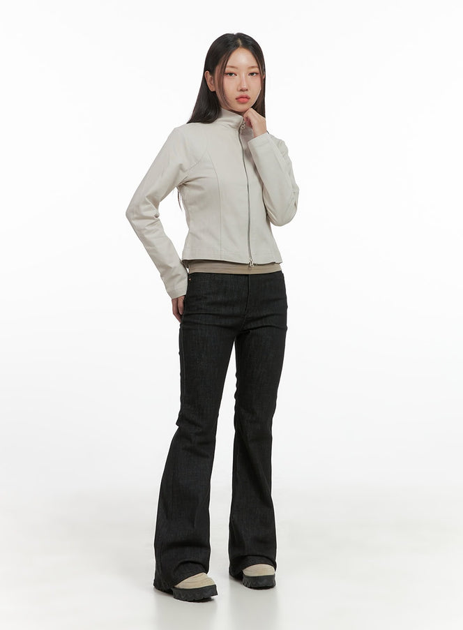 Noah Slim Bootcut Raw Denim Jeans CO404 in black, full-body front shot on model, slim fit bootcut silhouette, styled with cream zip-up moto jacket and chunky sneakers.