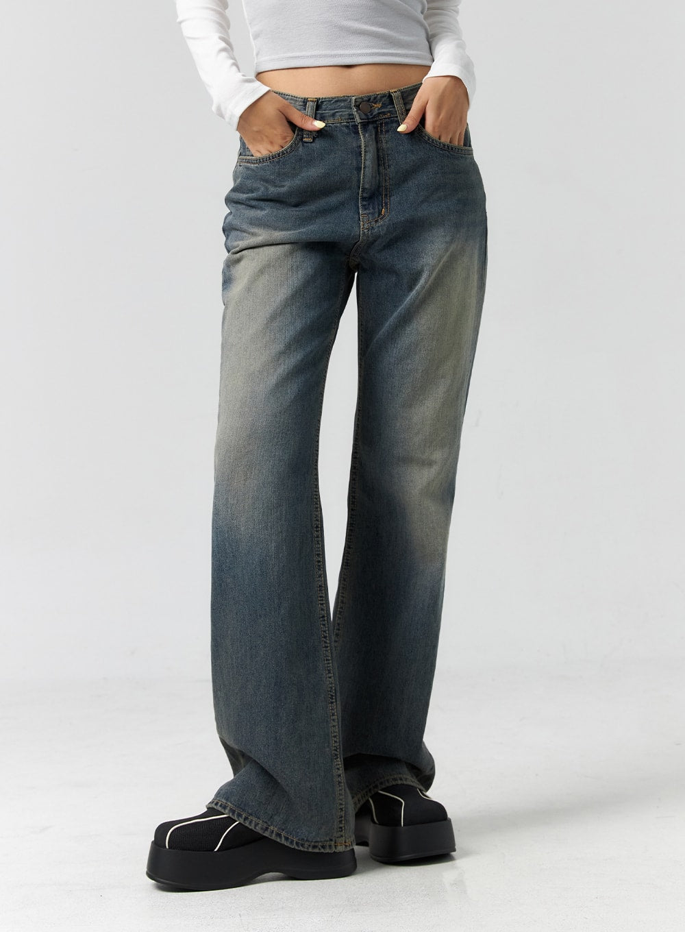 Vintage Wash Bootcut Jeans CS305 in blue, waist-to-hem close-up on model, showing vintage wash fading, five-pocket construction, and subtle bootcut flare, paired with white crop top.