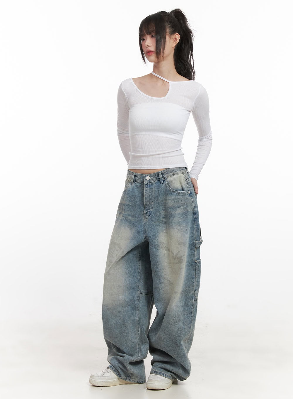 Abigail Camo-Print Carpenter Baggy Jeans CJ528 in blue, full-body front shot on model, wide baggy silhouette with washed camo denim, styled with white asymmetric crop top and white sneakers.