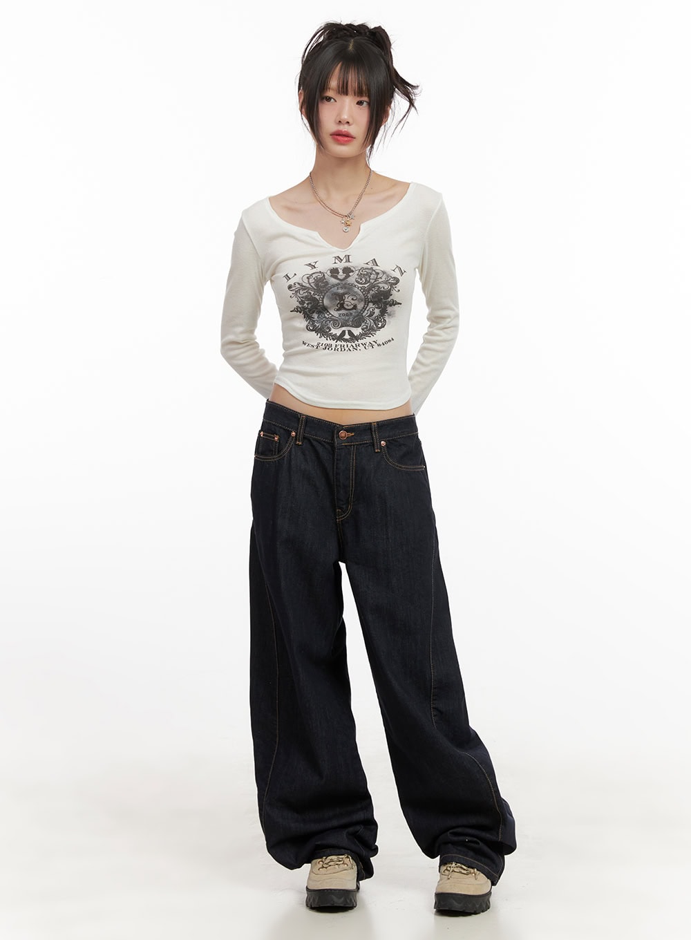 Fernanda Balloon-Fit Baggy Jeans CJ502 in dark blue, full-body front shot on model, low-waist balloon silhouette cotton denim, styled with white graphic crop long-sleeve and beige chunky sneakers.