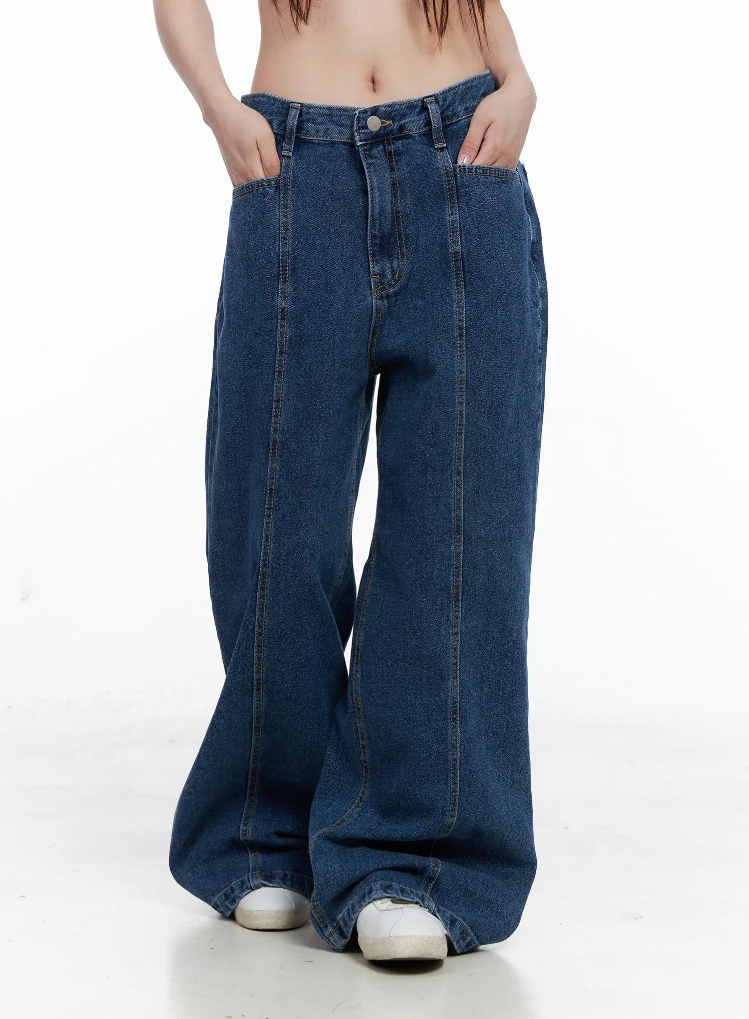 Eliza Seam Detail Relaxed Bootcut Jeans CO521 in washed blue, front waist-to-hem close-up on model, visible seam stitching, front pockets, low-rise waistband, white sneakers at hem.
