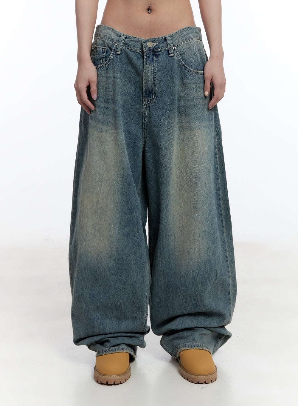 Jenna Relaxed-Fit Wide-Leg Jeans CU502 in blue, front waist-to-hem close-up on model, low-rise waistband with button fly, heavy washed fading, extreme wide-leg pooling at tan boots.