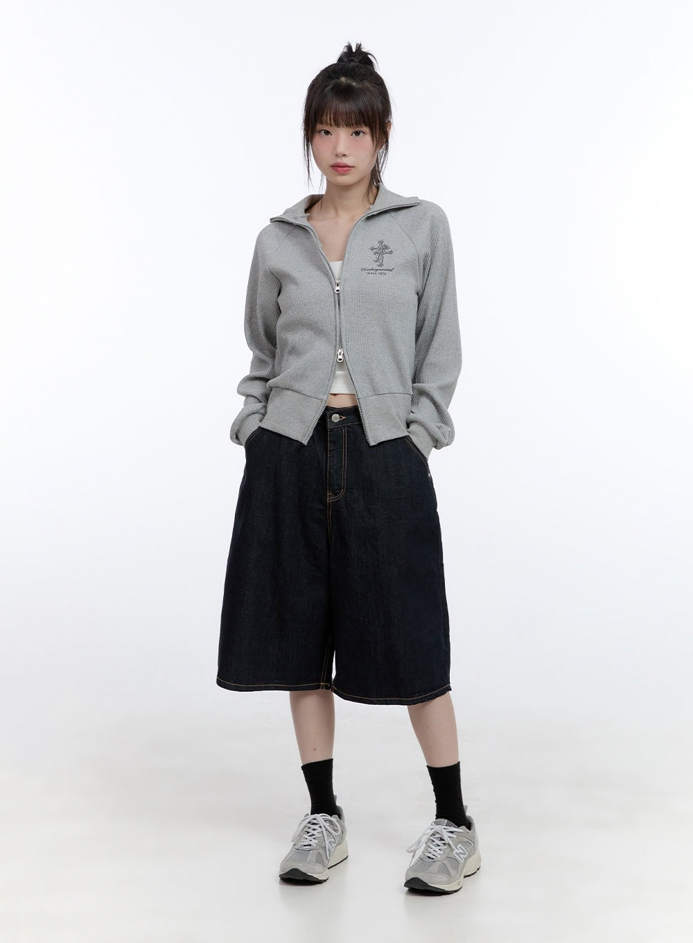 Dora Stitched Baggy Jorts CG413 in dark blue, full-body front shot on model, baggy knee-length denim styled with grey zip-up sweatshirt and New Balance sneakers.