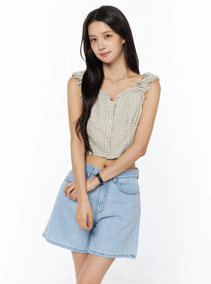 Plaid Ruffle Sleeveless Top CU522 in beige, front view on model, ruffle-trimmed straps and sweetheart neckline, paired with light blue denim shorts, relaxed pose.