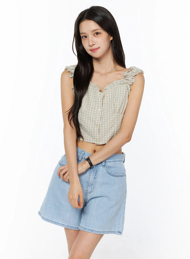 Plaid Ruffle Sleeveless Top CU522 in beige, front view on model, ruffle-trimmed straps and sweetheart neckline, paired with light blue denim shorts, relaxed pose.