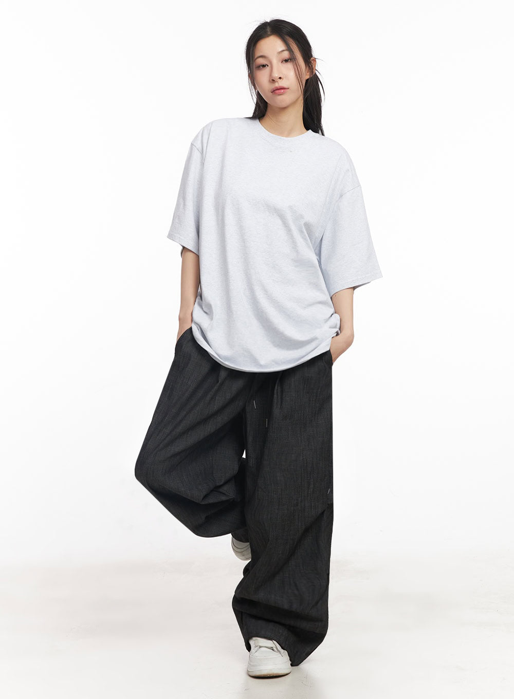 Pintuck Denim Sweatpants IY529 in black, full-body walking pose on model, ultra-wide baggy leg, elastic waist with drawstring, paired with oversized white tee and white sneakers.