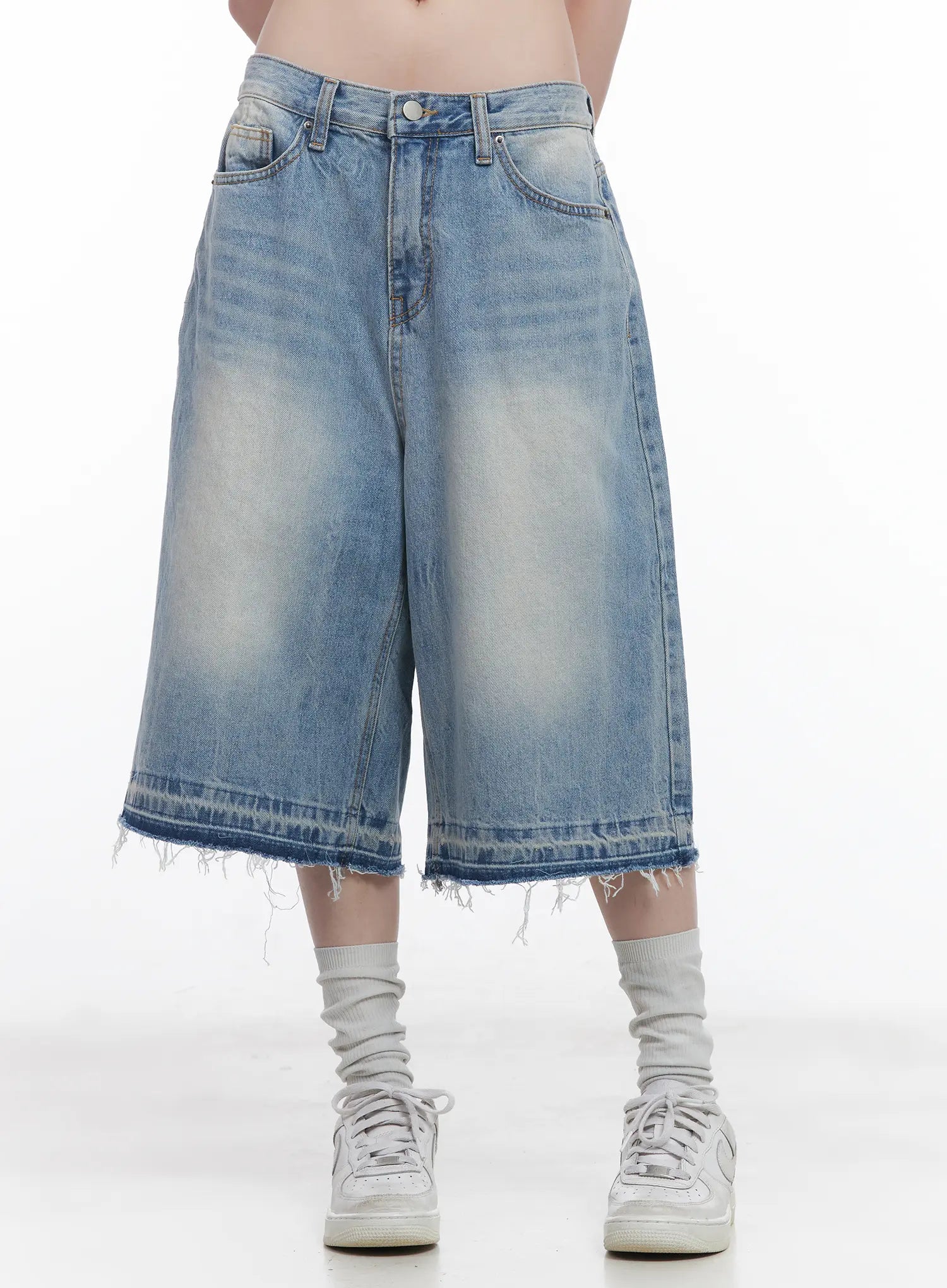 Light Wash Vintage Jorts CU519 in blue, front waist-to-ankle close-up on model, low-waist wide-fit cotton denim, washed fading, raw frayed hem, worn with white sneakers and grey socks.