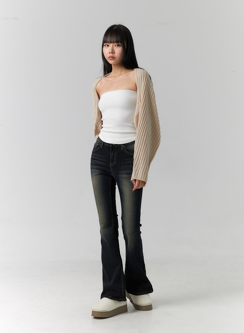 Washed Low Rise Bootcut Jeans CD308 in dark blue, front full-length model shot, arms relaxed, low-rise waistband and flared hem visible, styled with white tube top and oversized beige cardigan.