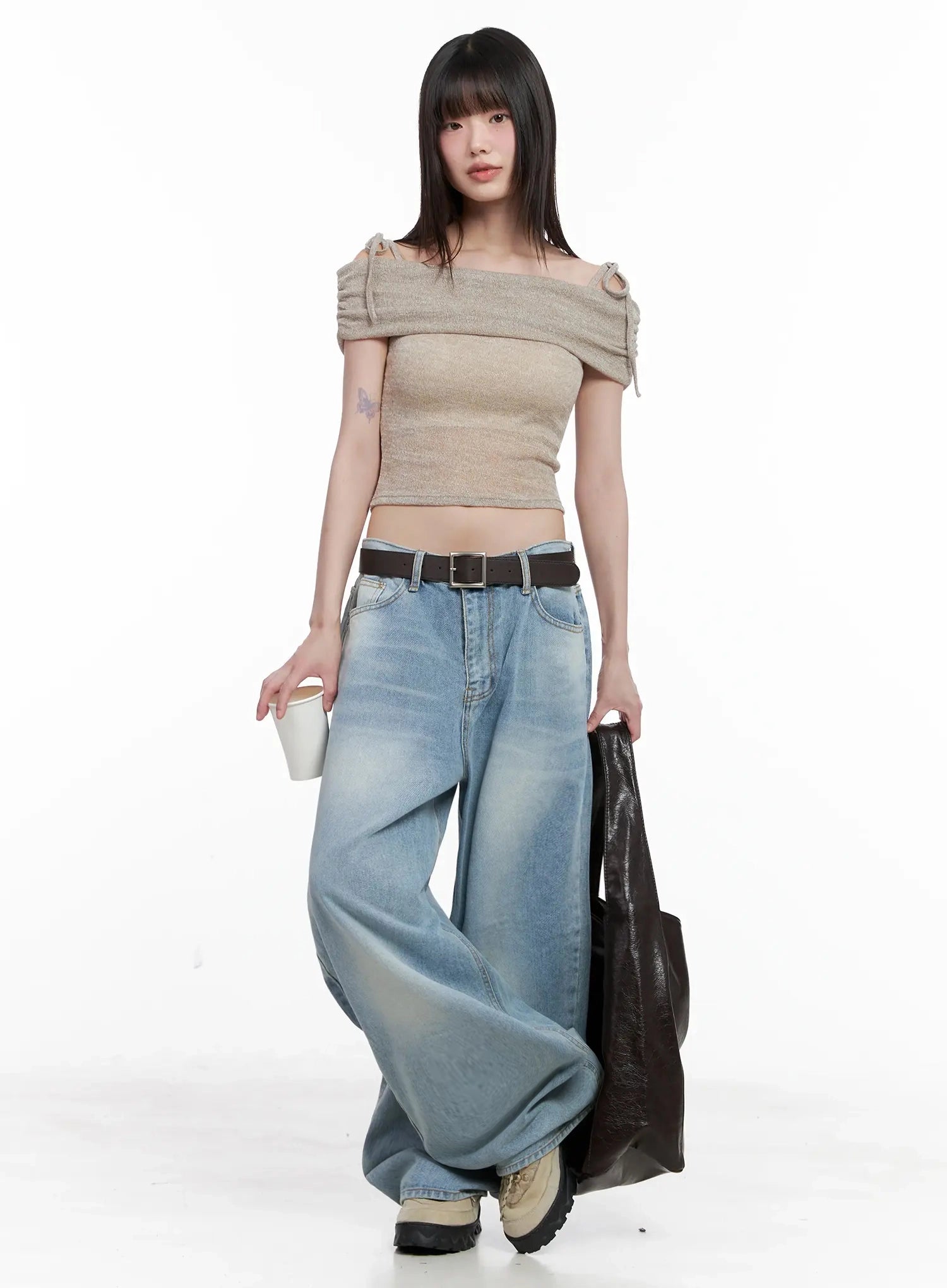 Dain Washed Wide-Leg Jeans IL531 in light blue, full-length editorial shot on model walking, belted waist, styled with beige off-shoulder crop top and dark tote bag.
