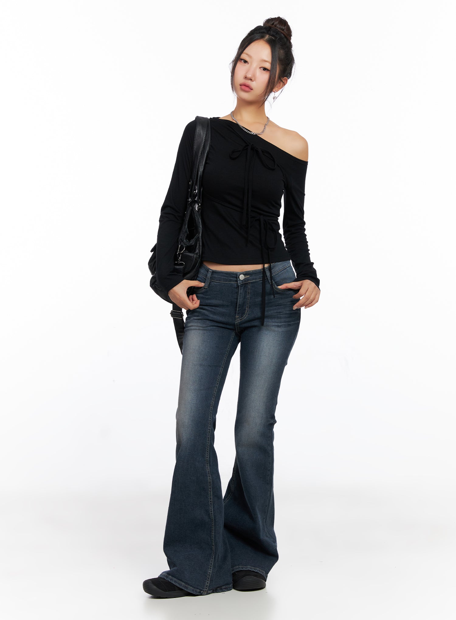 Melina Hip-Pad Low-Rise Flare Jeans CO514 in dark blue, full-body front on model, styled with black off-shoulder crop top and crossbody bag, long flare leg grazes floor.