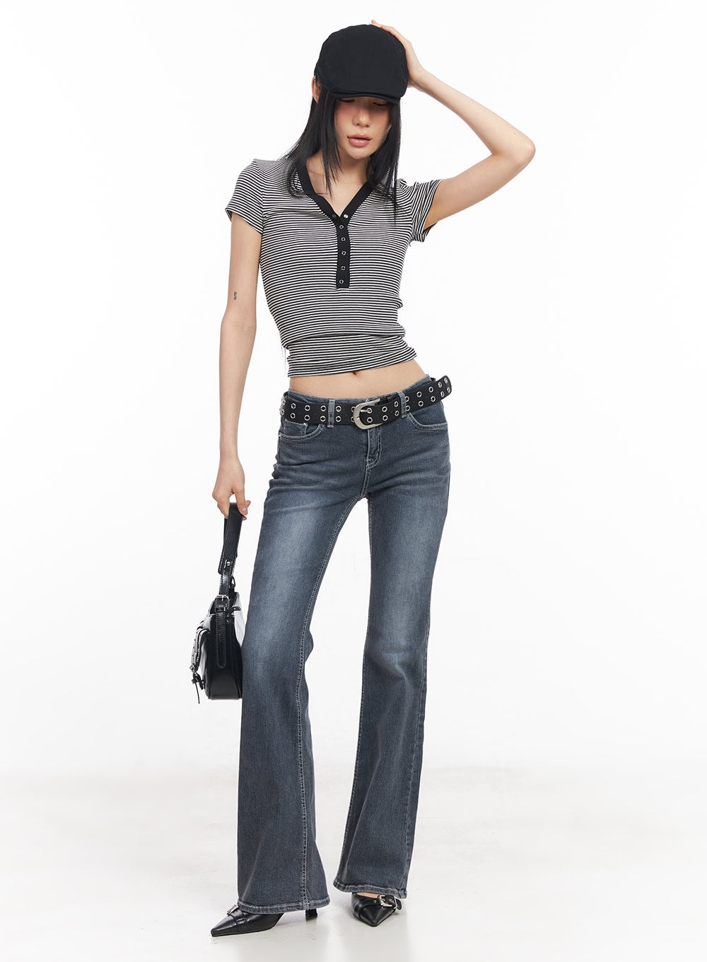 Nadeline Slim Bootcut Jeans CY528 in dark gray, full-body editorial shot on model wearing black cap and striped crop top, slim bootcut silhouette with grommet belt and mini bag.