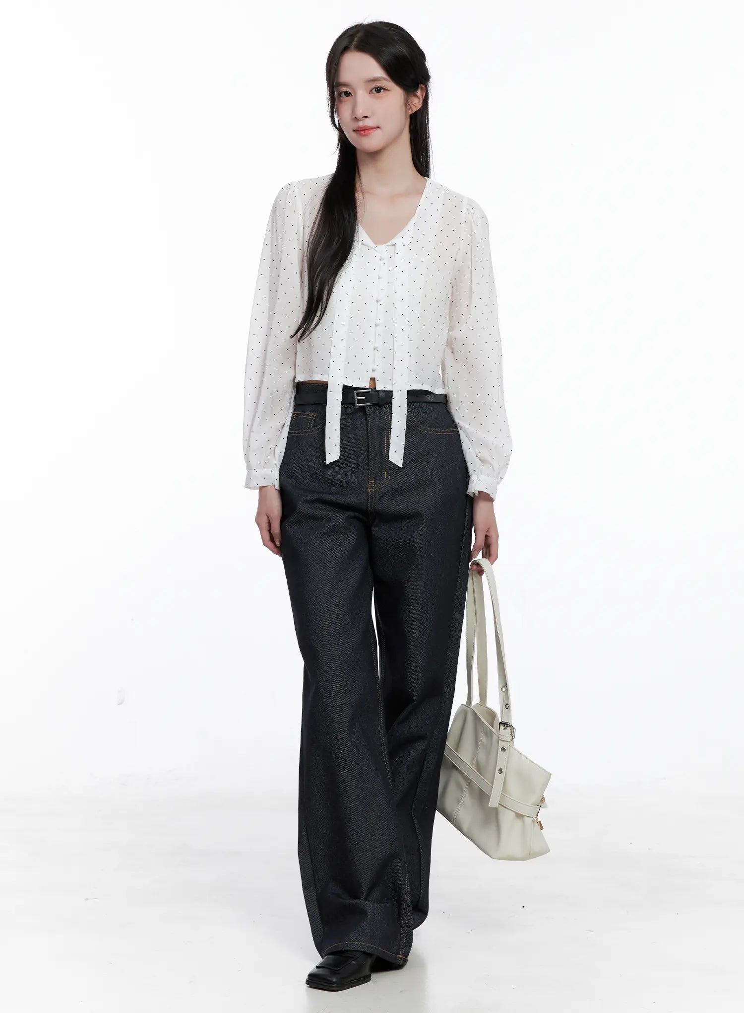 Reyna Non-Fade Relaxed Jeans CS519 in dark blue, full-body front worn by model, relaxed wide-leg cotton denim styled with white polka-dot crop blouse, black belt, and cream tote bag.