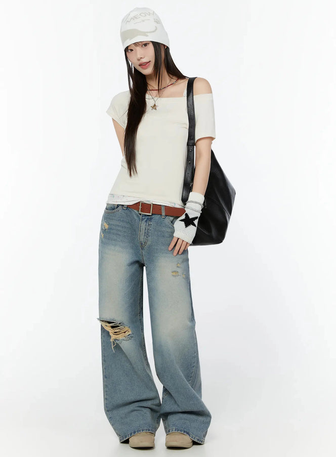 Colette Distressed Wide Leg Jeans IU518 in blue, full-body front shot on model styled with off-shoulder white tee, beanie, star gloves, and black leather tote bag.