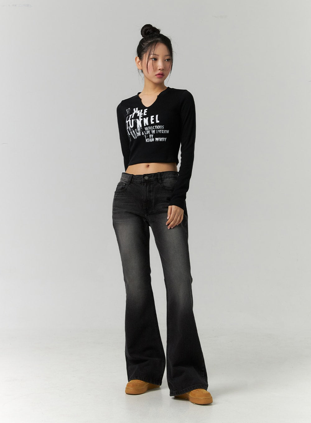 Low Rise Bootcut Jeans CD304 in black, front full-body shot on model standing straight, low-rise waistband and flared hem visible, styled with black crop top and tan platform shoes.