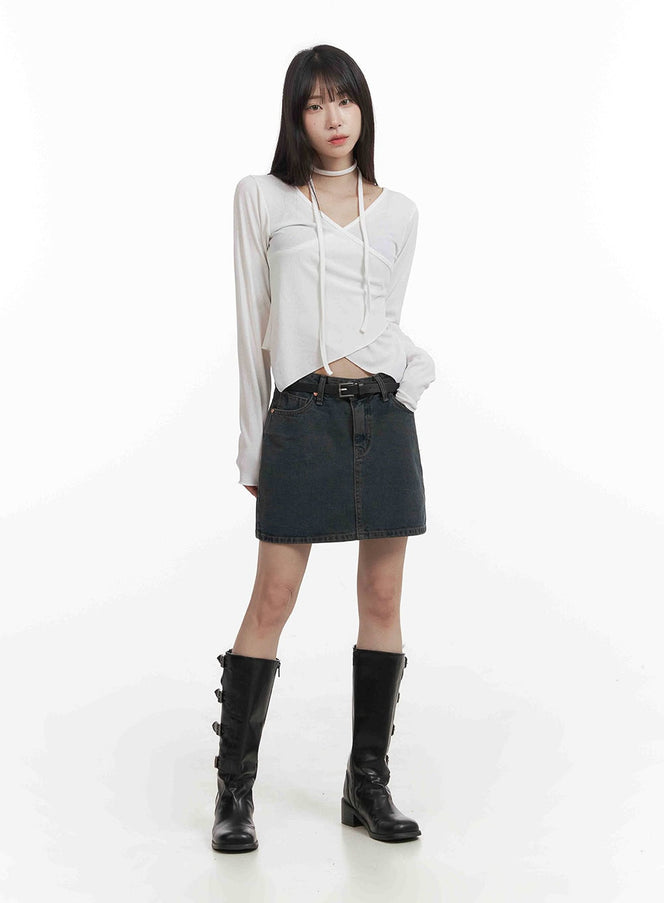 Low Wash Indigo Dream Denim Mini Skirt CY407 in dark gray, full-body front shot on model, belted low waist, A-line mini length, styled with white wrap crop top and black boots.