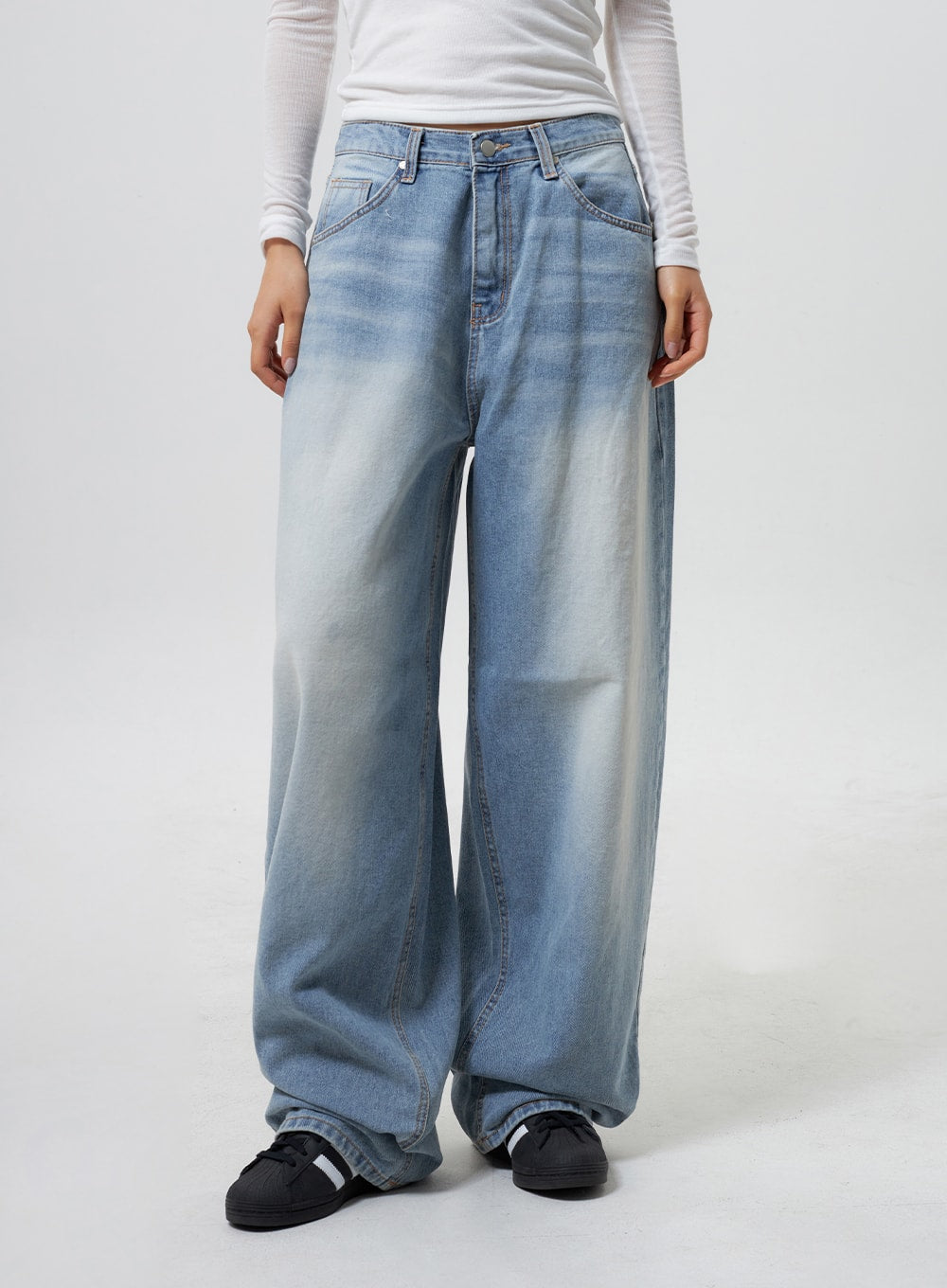 Low Rise Baggy Jeans CY324 in light blue, front waist-to-hem close-up on model, low-rise waistband with button fly, wide baggy leg silhouette, worn with white long-sleeve top.